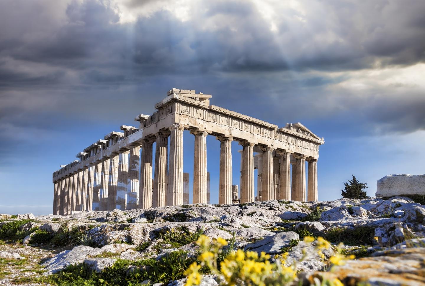Sunlight peaks through storm clouds over the Acropolis in Athens, Greece
