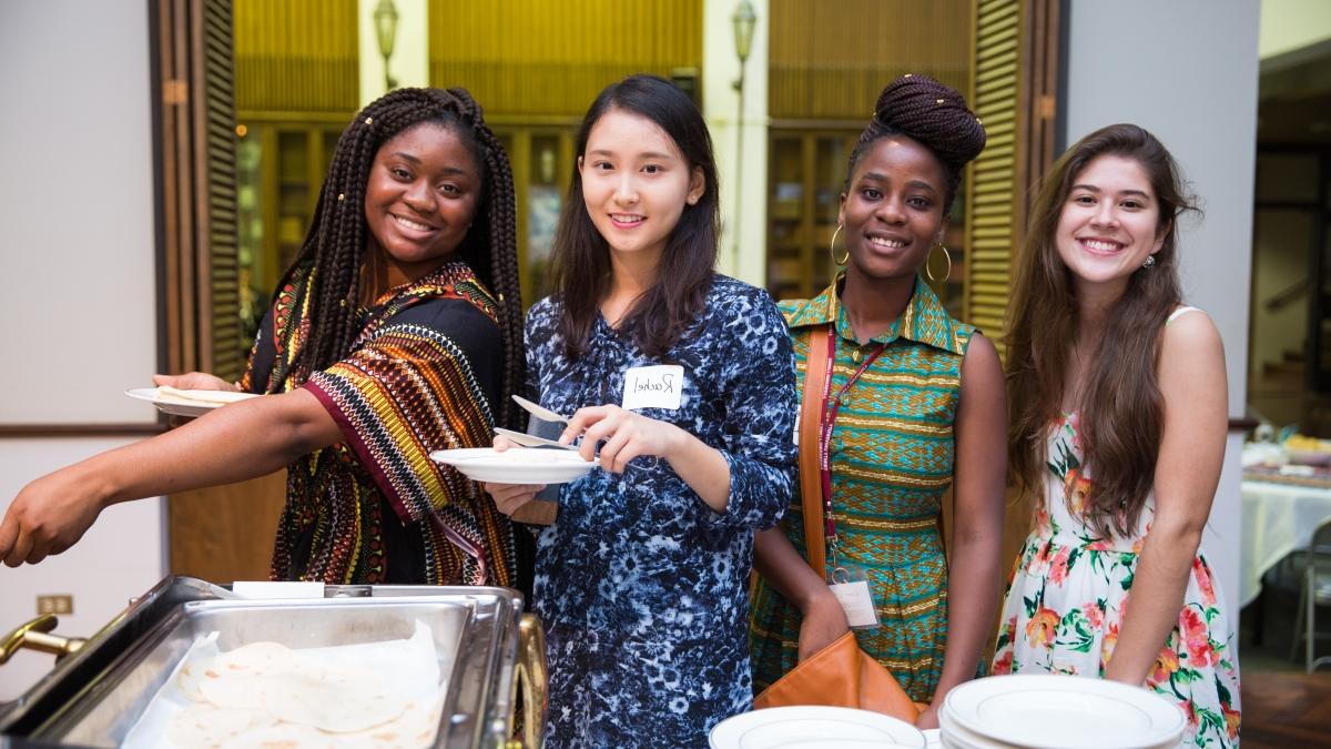four women pose and smile during the international student reception in Chapman Great Hall